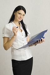 Image showing Business girl listens and makes notes in a folder