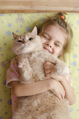 Image showing little girl hugging cat lying on a mattress floor