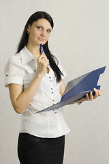 Image showing Business girl listens and makes notes in a folder