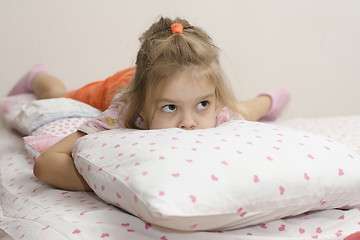 Image showing girl lying and hiding his face in pillow looking right