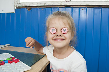 Image showing Girl stuck in eyes of mosaic with letter I and smiles