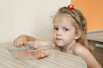Image showing child with the inquiring views eats porridge