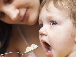 Image showing mother is feeding small child porridge with spoon