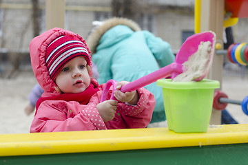 Image showing little girl pours sand bucket in sandbox