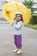 Image showing Small girl standing with the yellow umbrella