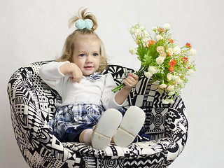 Image showing little girl sitting on chair with bunch of flowers