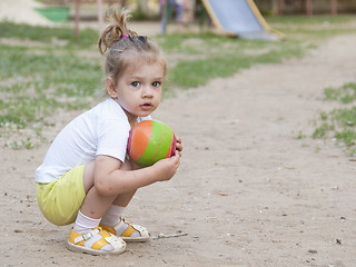 Image showing Little girl sitting on his haunches with a ball Playground