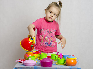 Image showing Girl plays child kitchen utensils