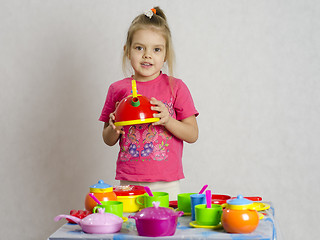 Image showing Girl plays child kitchen utensils