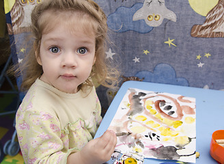 Image showing Two-year-old girl is painting at table and looks