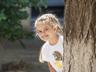 Image showing child of four years peeping from behind a tree