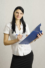 Image showing Business girl listens and makes notes in a folder