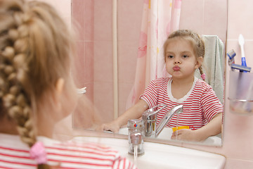 Image showing Four-year-old girl rinse teeth after cleaning in bathroom