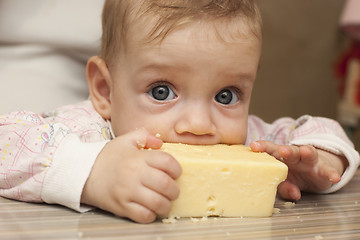 Image showing Seven-month baby eats a big piece of cheese