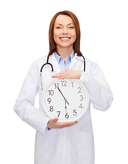 Image showing smiling female doctor with wall clock