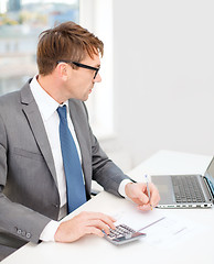 Image showing businessman with computer, papers and calculator