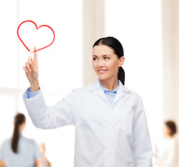 Image showing smiling female doctor pointing to heart