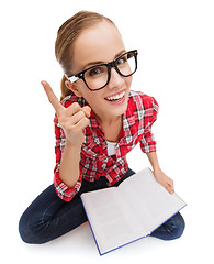 Image showing smiling teenage girl in eyeglasses reading book