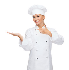 Image showing smiling female chef holding something on hand