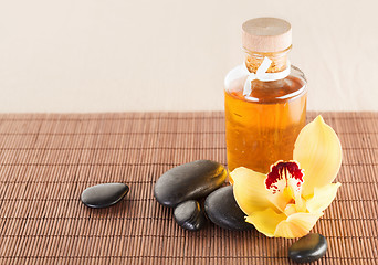 Image showing essential oil, massage stones and orchid flower