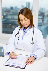 Image showing busy doctor with laptop computer and clipboard