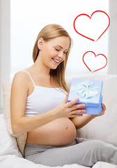 Image showing smiling pregnant woman opening gift box