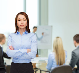 Image showing smiling businesswoman with crossed arms at office