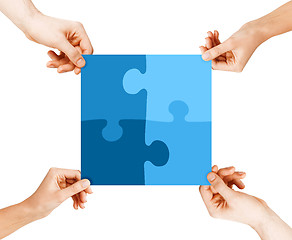 Image showing four hands connecting puzzle pieces