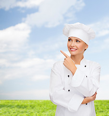 Image showing smiling female chef pointing finger to sonething