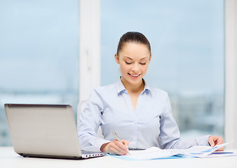 Image showing businesswoman with laptop and charts in office