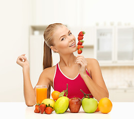 Image showing smiling woman with organic food eating strawberry