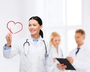 Image showing smiling female doctor pointing to heart