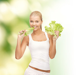 Image showing smiling woman biting lettuce