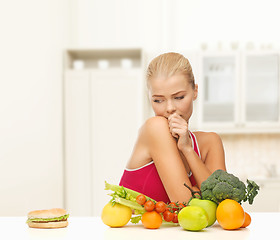 Image showing doubting woman with fruits and hamburger