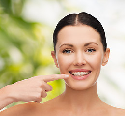 Image showing young calm woman pointing to her mouth