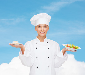 Image showing smiling female chef with salad and cake on plates