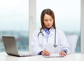 Image showing busy doctor with laptop computer and clipboard