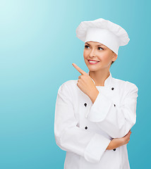 Image showing smiling female chef pointing finger to sonething