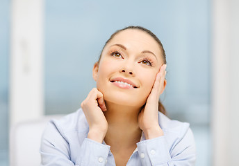 Image showing smiling businesswoman dreaming in office