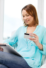 Image showing happy woman with tablet pc and credit card at home