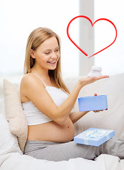 Image showing smiling pregnant woman with gift box and bootees