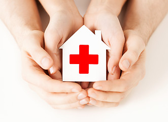 Image showing hands holding paper house with red cross