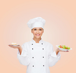 Image showing smiling female chef with salad and cake on plates