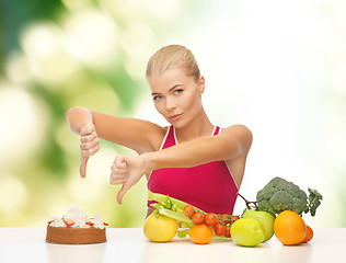 Image showing woman with fruits showing thumbs down to cake