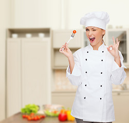 Image showing smiling female chef with fork and tomato