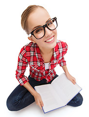 Image showing smiling teenage girl in eyeglasses reading book