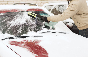 Image showing closeup of man cleaning snow from car