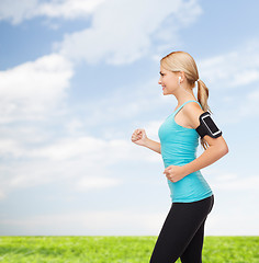 Image showing sporty woman running with smartphone and earphones