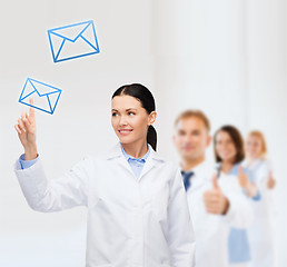 Image showing smiling female doctor pointing to envelope