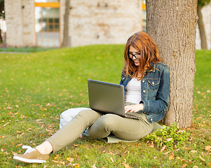 Image showing smiling teenager in eyeglasses with laptop